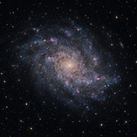 KI-generiertes Bild: Redaktionelle KI-Illustration der Dreiecksgalaxie M33 mit locker gewundenen Spiralarmen und Sternentstehungsgebieten.