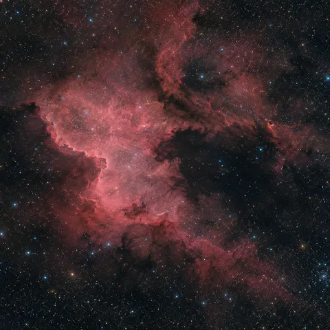 KI-generiertes Bild: Redaktionelle KI-Illustration des Nordamerikanebels NGC 7000 mit markanter Küstenkontur und dunkler Golfregion.