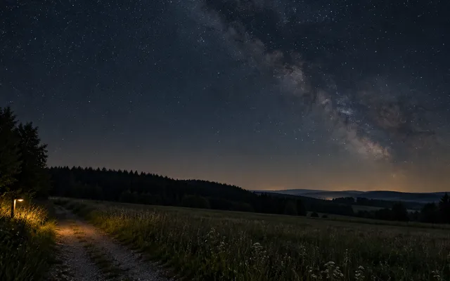 KI-generiertes Bild: KI-generierte redaktionelle Aufnahme eines dunklen Wiesenwegs mit abgeschirmter Beleuchtung und natürlichem Sternenhimmel.